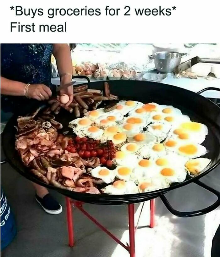 Large pan filled with many fried eggs, sausages, bacon, and tomatoes being cooked, depicting food and eating memes.