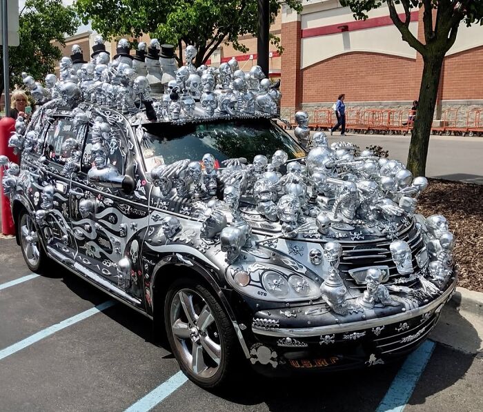 Car covered in numerous silver skull decorations, creating a cursed photo that makes zero sense but is memorable.