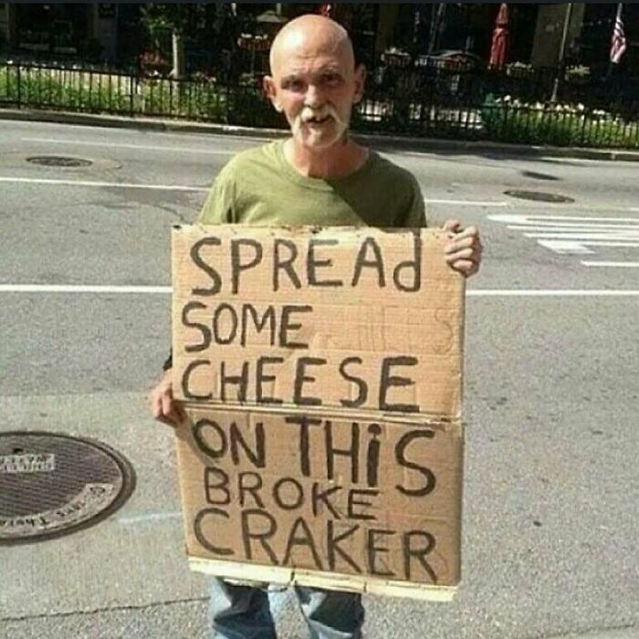 Man holding a cardboard sign with a misspelled message, a cursed photo that makes zero sense on a city street.