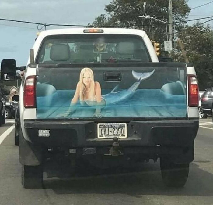 Pickup truck with a tailgate painted to show a blonde mermaid lying in water, an example of cursed photos that confuse viewers.