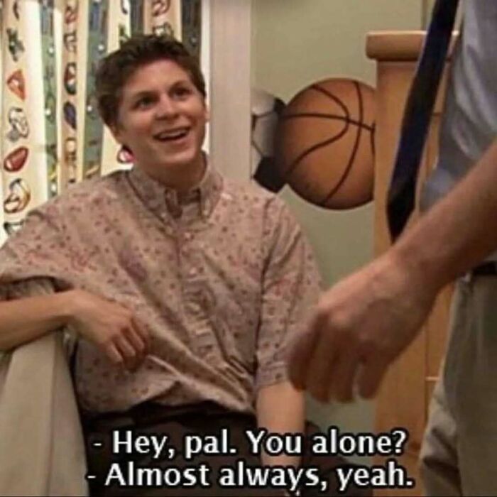 Young man smiling while sitting indoors with dialogue about being almost always alone, relatable meme for existential crisis.