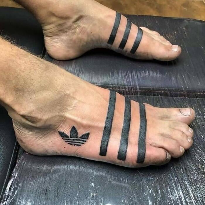 Foot tattoos with thick black stripes and a logo design, showcasing ink fails that turned bad ideas into permanent regrets.