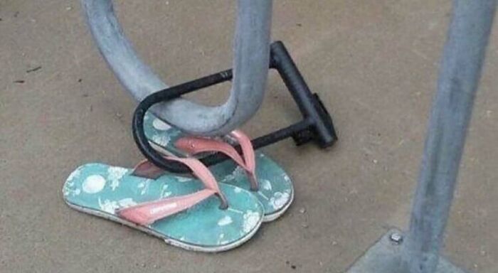 Flip-flops locked to a bike rack with a bike lock in a cursed photo that makes absolutely zero sense.