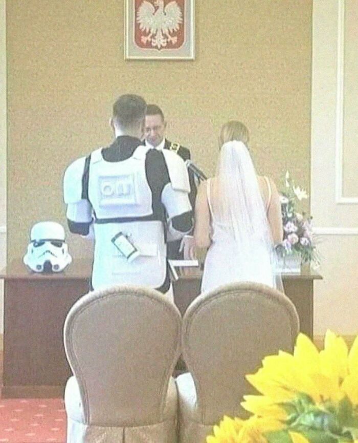 Bride and groom standing before officiant with groom dressed as a stormtrooper in a cursed photo that makes zero sense.