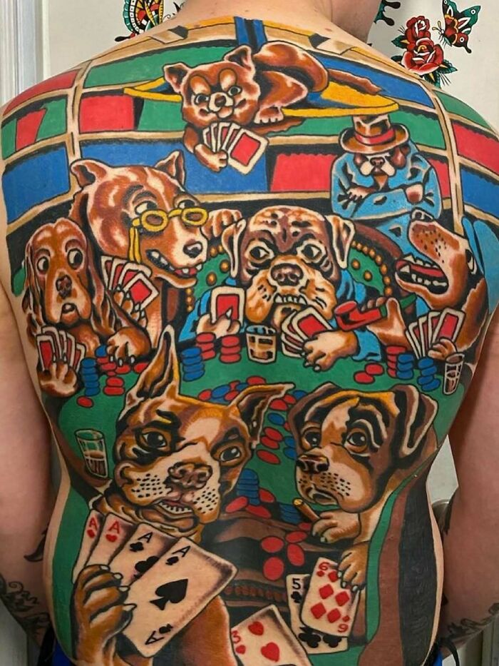 Colorful back tattoo of dogs playing poker with vivid cards and chips, a cursed photo that makes zero sense.