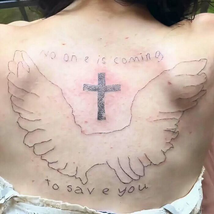 Back tattoo with uneven ink, featuring a cross and poorly drawn wings, a clear example of ink fails and bad tattoo ideas.