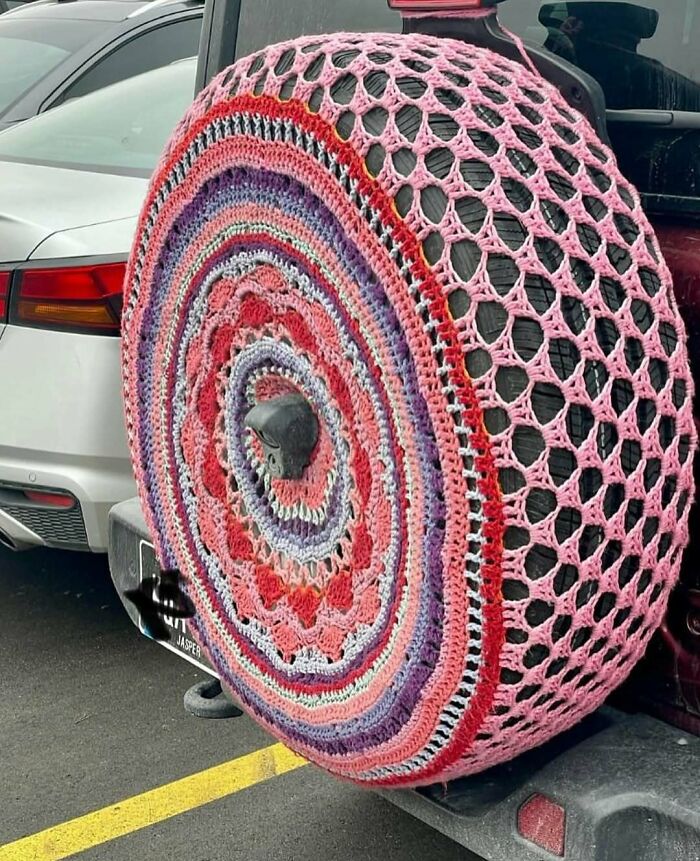 Car spare tire covered with a colorful crocheted cover, an example of cursed photos that make zero sense.