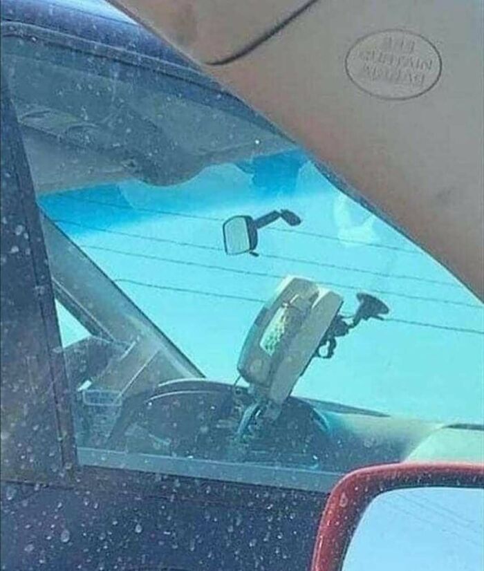 Old-school car payphone mounted on dashboard, creating one of the 79 cursed photos that make absolutely zero sense.