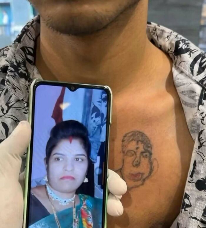 Man showing a poorly done ink tattoo portrait on chest alongside the original photo on a smartphone screen.