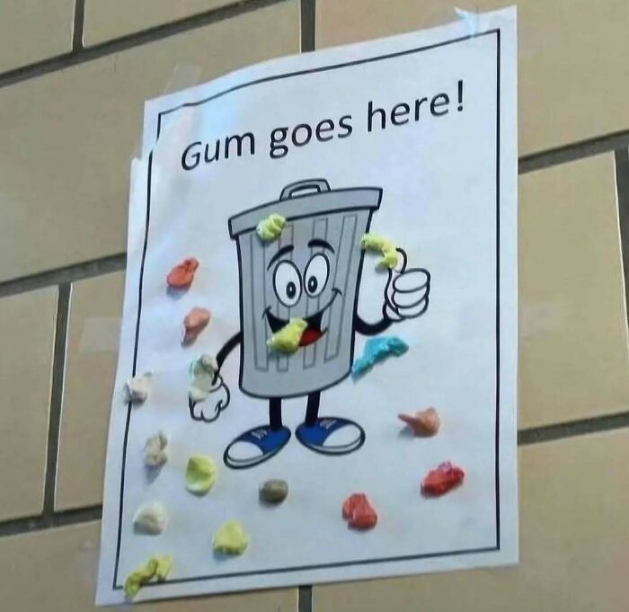 Sign with cartoon trash can saying gum goes here covered in gum, a cursed photo that makes zero sense but sticks in minds.