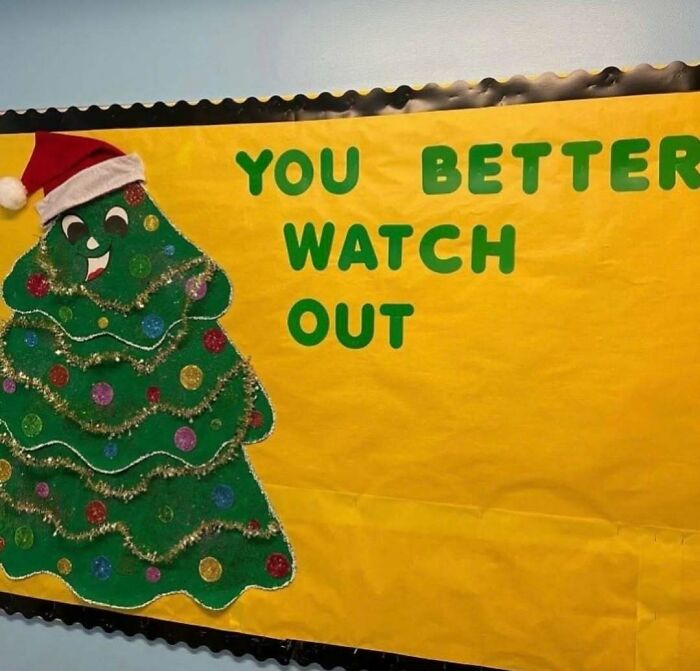 Cursed photo of a decorated Christmas tree with a Santa hat and partial warning message on a yellow bulletin board.