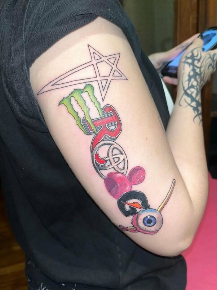 Tattoo on arm featuring strange combination of symbols and logos in a cursed photo that makes zero sense.