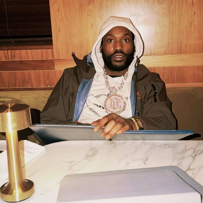 Man wearing a hood and large chain necklace sitting at a table inside a custom $2.5 million mobile mansion.