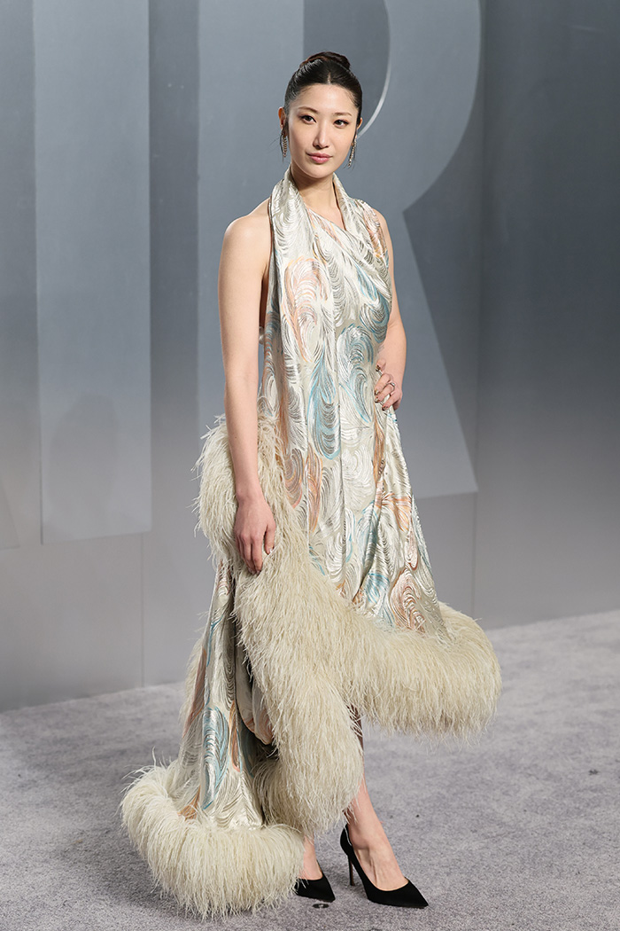 Woman wearing an extravagant dress with feather trim, showcasing one of the biggest fashion fails at Oscars afterparties.