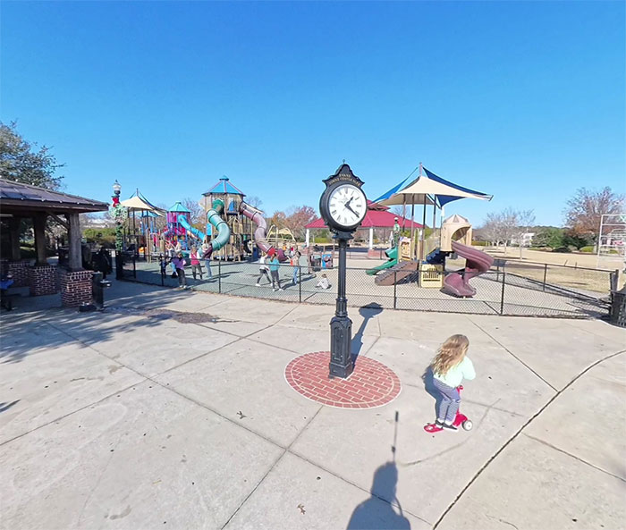 Outdoor playground with children playing near a clock tower, related to mom of 5yo arrested for crimes at festival crowd.