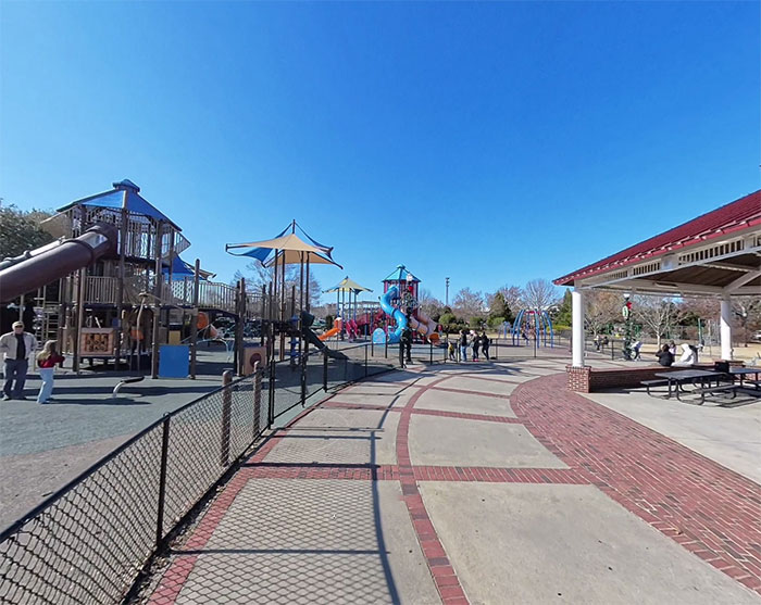 Playground area with slides and climbing structures, with families and children enjoying the festival crowd outdoors.