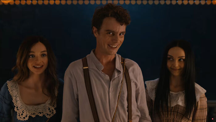 Three young actors in period costumes smiling in a dark setting from the Scary Movie 6 trailer spoofing a horror hit.