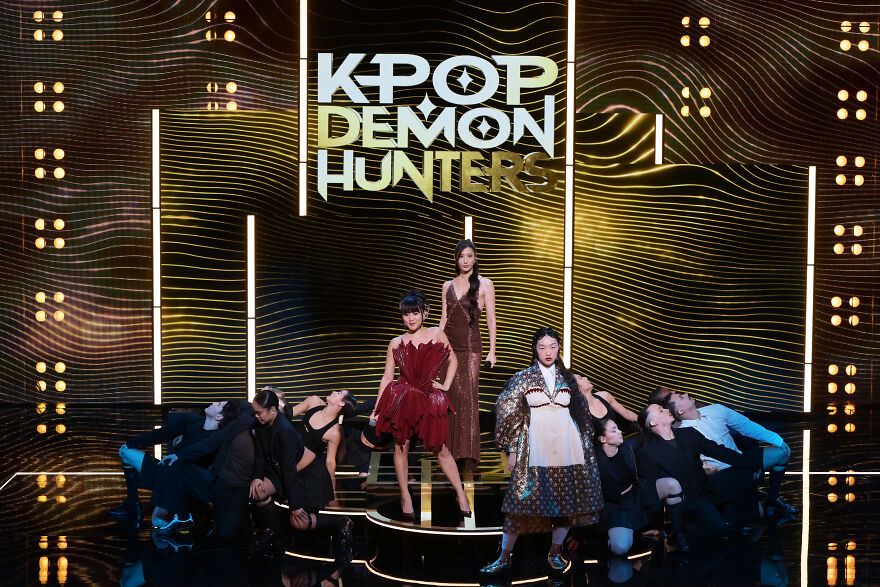 Performers on stage under Kpop Demon Hunters sign, showcasing the best original song power in a vibrant music setting.