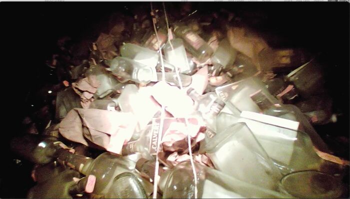 Pile of old, dusty glass bottles and containers found in a creepy old home with bizarre hidden items.