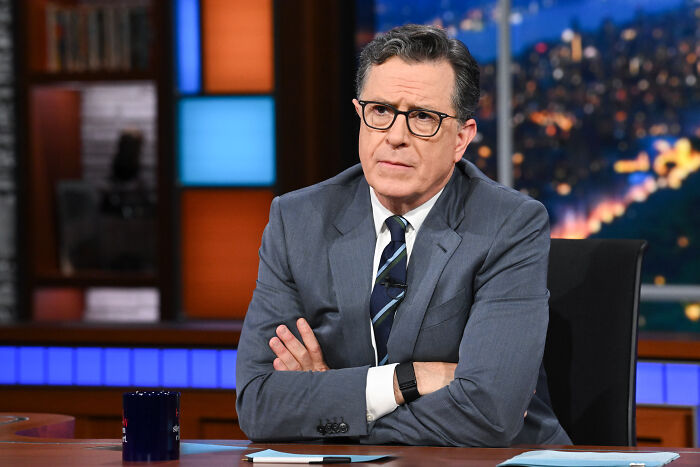 Stephen Colbert sitting at a desk during a talk show, discussing the new Lord of the Rings movie plot and timeline. Stephen Colbert sitting at a desk during a talk show, discussing the new Lord of the Rings movie plot and timeline.