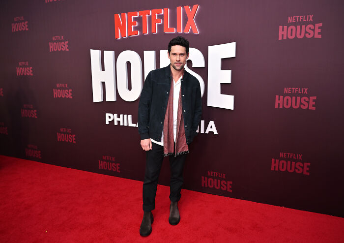 Actor posing on the red carpet at Netflix House event, related to Virgin River star Brady and season 7 cliffhanger.