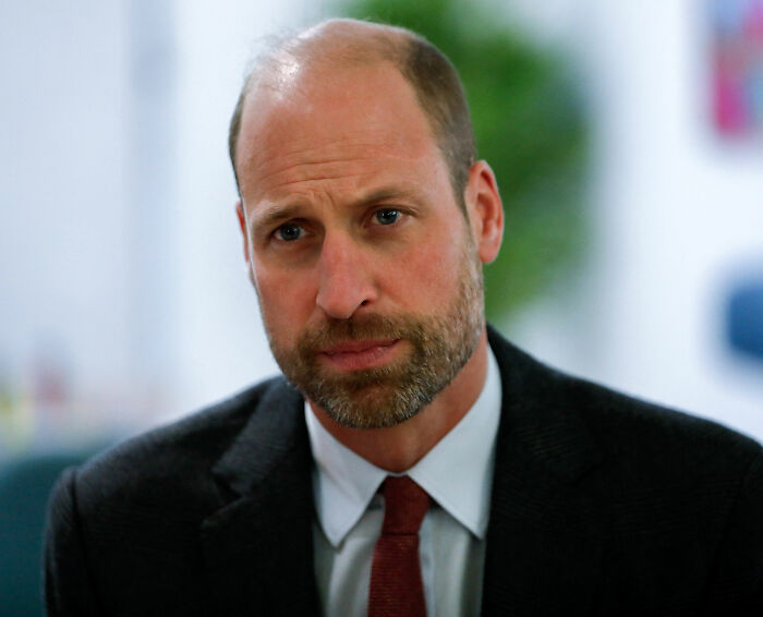 Prince William with thoughtful expression, wearing a suit and tie, caught on camera getting into character in a close-up.