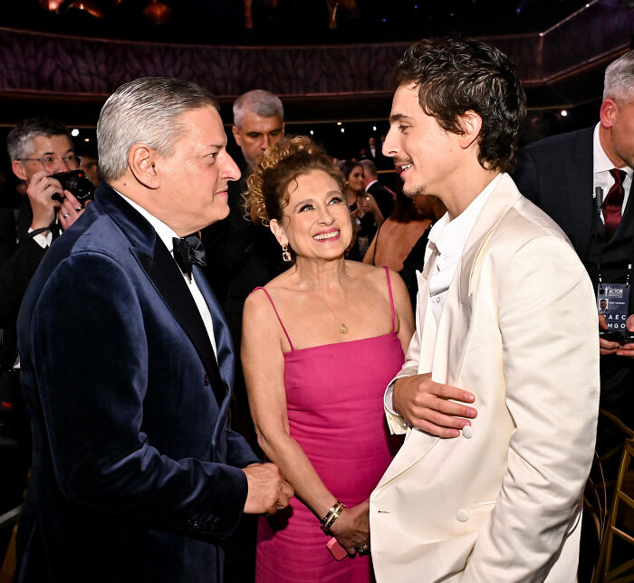 Timoth&eacute;e Chalamet talking with two people at the Actor Awards, sparking wild theories about his date and presence.
