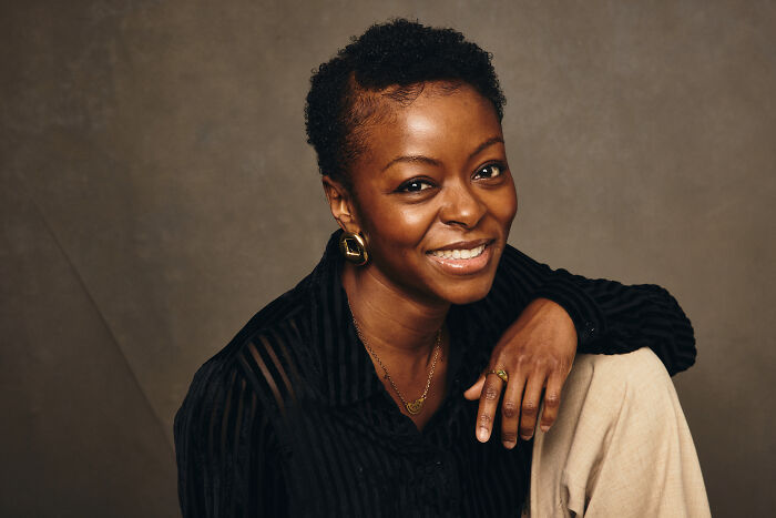 Smiling woman in a black shirt and beige pants posing against a neutral background, related to Ryan Coogler X-Files reboot.