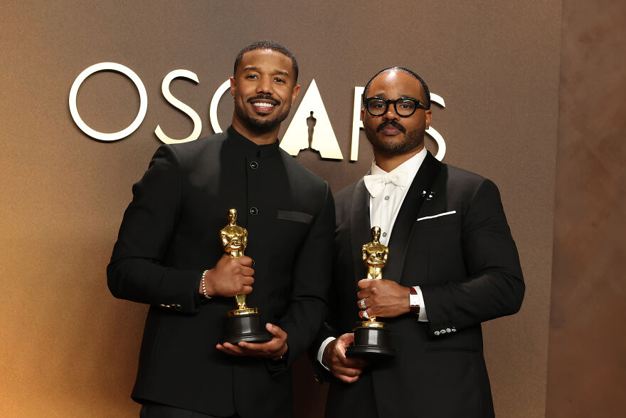 Michael B. Jordan and another man holding Oscars at the awards ceremony celebrating historic Best Actor wins.