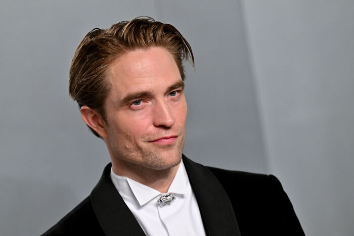 Robert Pattinson attending an event, wearing a black suit and white shirt, related to his role in Dune 3 villain character.