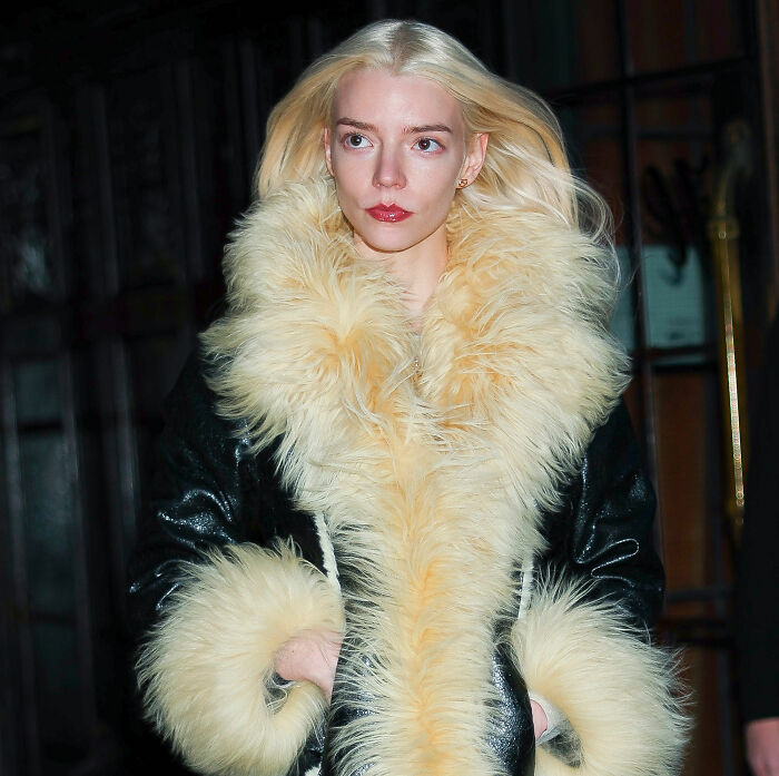 Anya Taylor-Joy in a black coat with large fur collar and cuffs, sparking heated debate among fans after interview appearance.