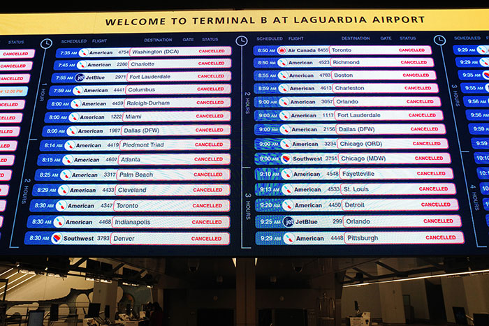 Quadro de status de voo no Aeroporto LaGuardia mostrando vários voos cancelados, incluindo a Air Canada, após incidente de acidente.