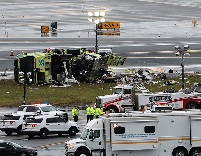 Equipes de emergência no aeroporto LaGuardia, perto dos destroços do acidente da Air Canada envolvendo comissário de bordo.