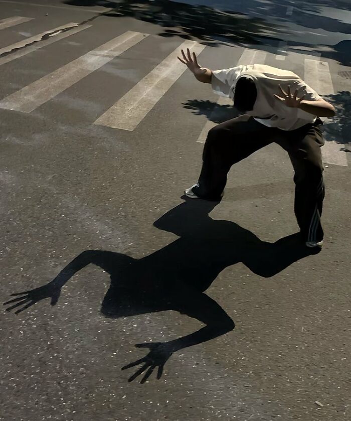Person striking creative pose on crosswalk casting a dynamic shadow, showcasing hilarious and creative poses skillfully pulled off.