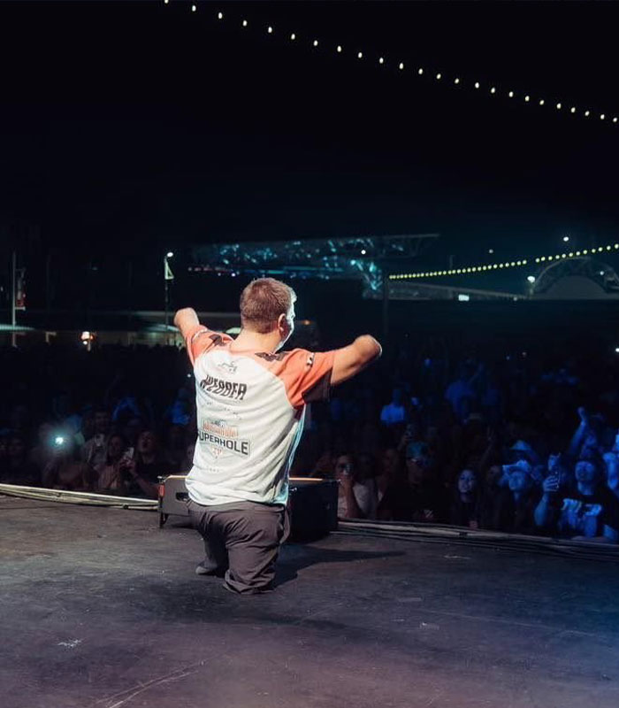 Man with no arms or legs performing on stage at night in front of a large audience with lights overhead.