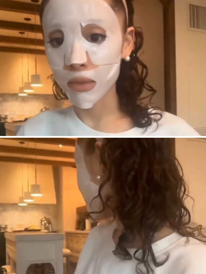 Ariana Grande wearing a white facial mask at home, sparking plastic surgery rumors with her latest look.