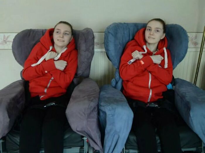 Two identical young women in red hoodies sitting in separate armchairs, illustrating disturbing real life facts.