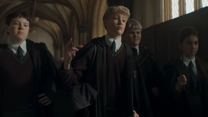 Young Hogwarts students in robes inside a dimly lit corridor, related to Harry Potter fans trolling a character on TikTok