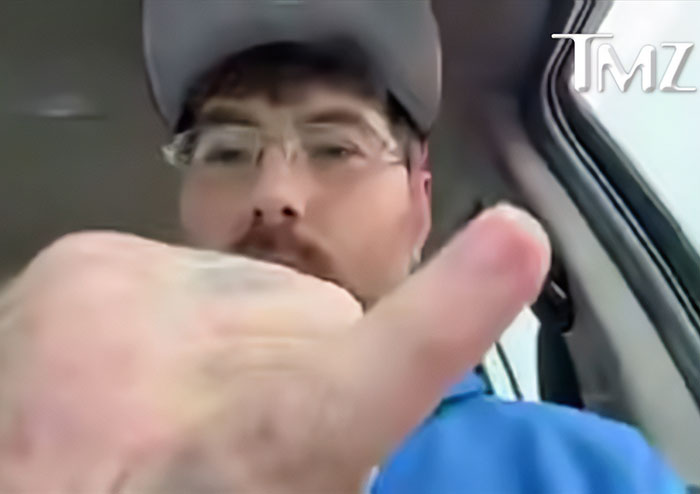 Man wearing glasses and cap in a car, featured in a video related to owner of world's tiniest package apology.