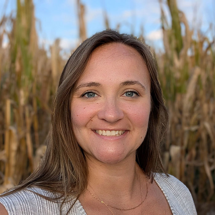 Smiling woman with long hair outdoors in a field, related to mom arrested for crimes in front of festival crowd.