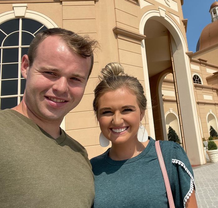 Joseph Duggar smiling with a woman outdoors in front of a large building, related to Josh Duggar misconduct discussion.