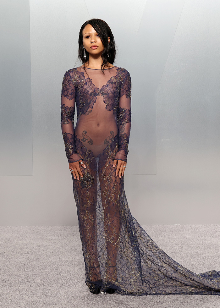 Woman wearing a sheer lace dress with tattoos visible, showcasing one of the biggest fashion fails from Oscars afterparties.