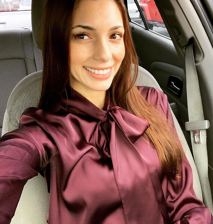 Mulher da Flórida sorrindo dentro de um carro, vestindo uma blusa de cetim bordô com detalhe de gravata borboleta na gola. Mulher da Flórida sorrindo dentro de um carro, vestindo uma blusa de cetim bordô com detalhe de gravata borboleta na gola.