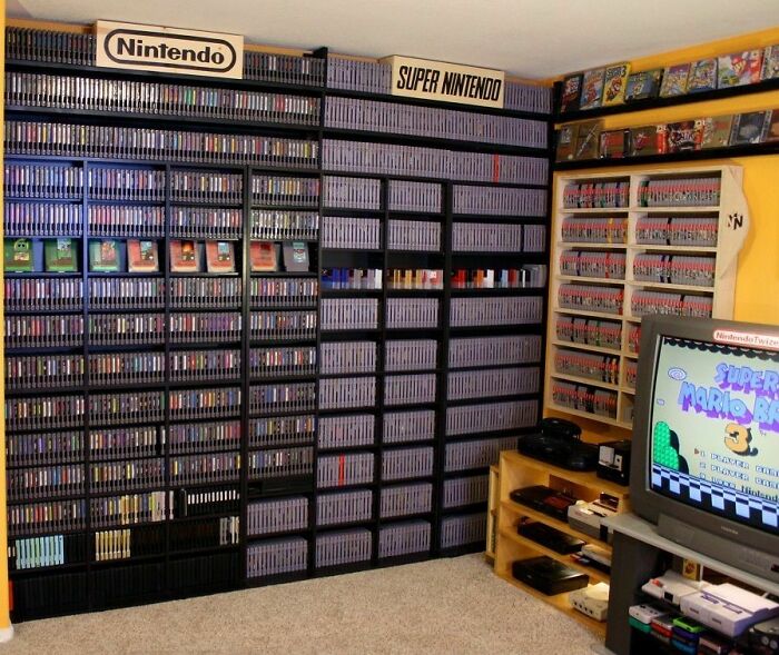 Extensive Nintendo and Super Nintendo game collection displayed on shelves in a dedicated gaming room.