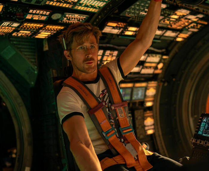 Ryan Gosling wearing glasses and an orange harness inside a high-tech cockpit, sparking fan speculation at premiere.