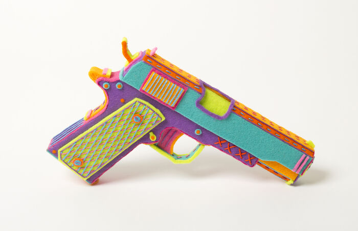 Colorful handcrafted paper gun sculpture by French artist duo, showcasing incredible detail in ordinary paper art.