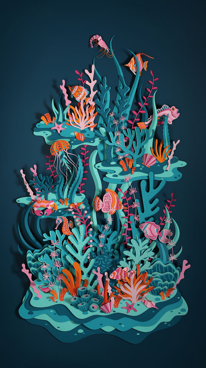 Intricate handcrafted paper artwork depicting an underwater world with colorful fish and coral by French artist duo.