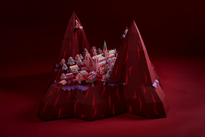 Intricate handcrafted paper village nestled between two red mountain peaks, showcasing detailed miniature architecture.