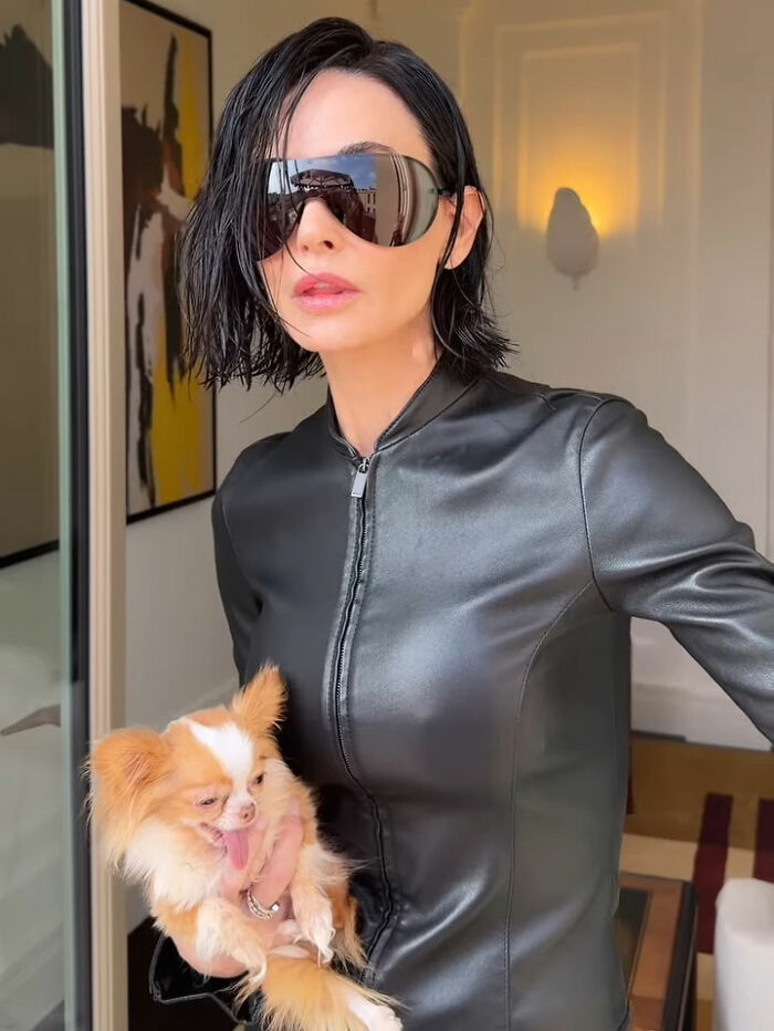 Demi Moore in a black leather outfit and sunglasses holding a small dog, showcasing a bold red carpet transformation.