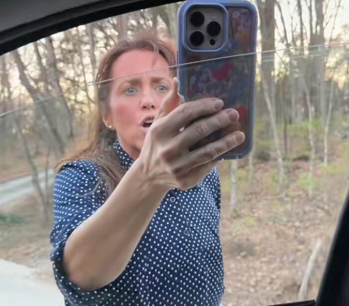 Michelle Duggar holding a phone, appearing upset and confronting someone outdoors near a wooded area.